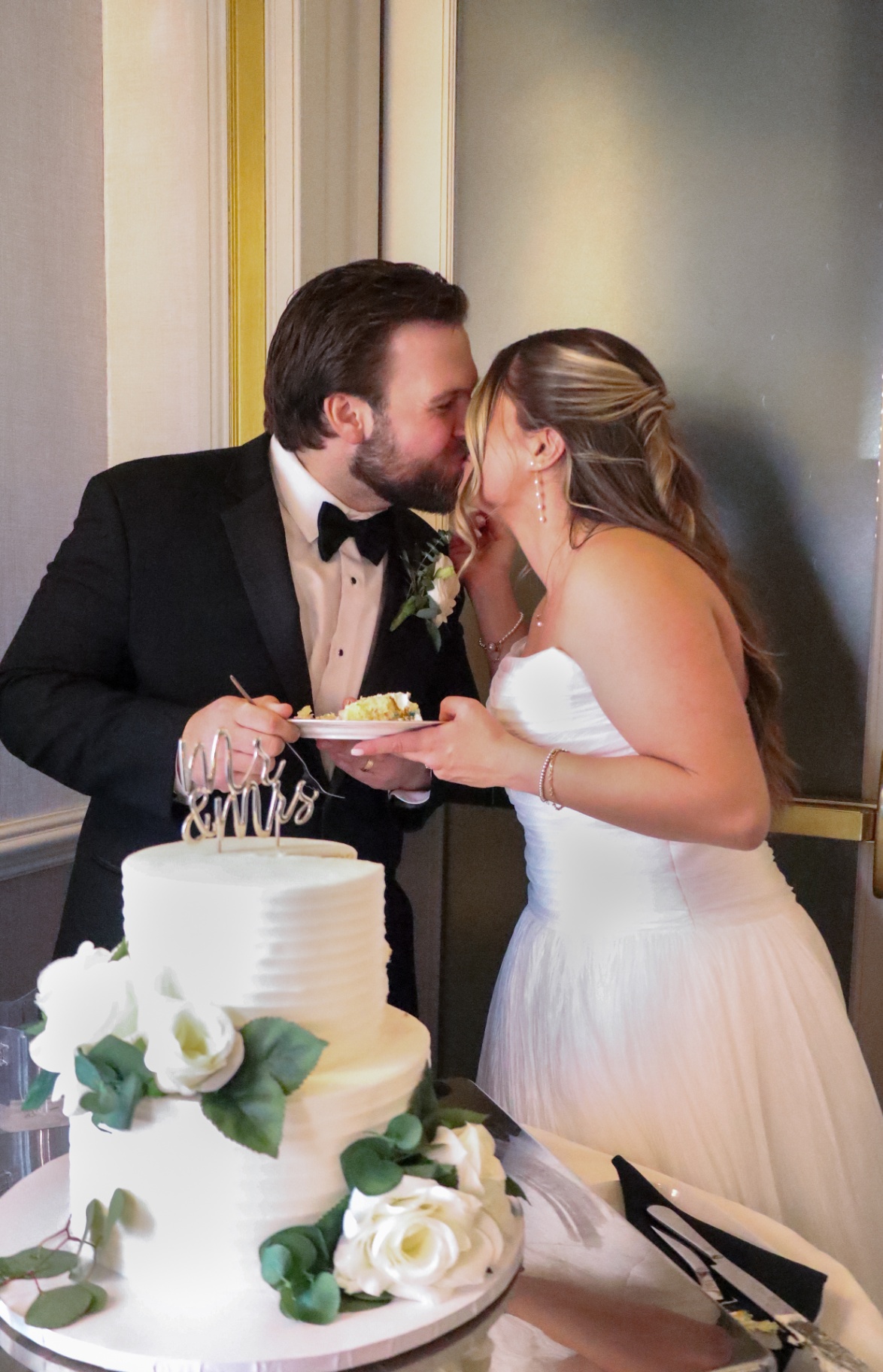 Bride and groom sharing a kiss while feeding each other wedding cake