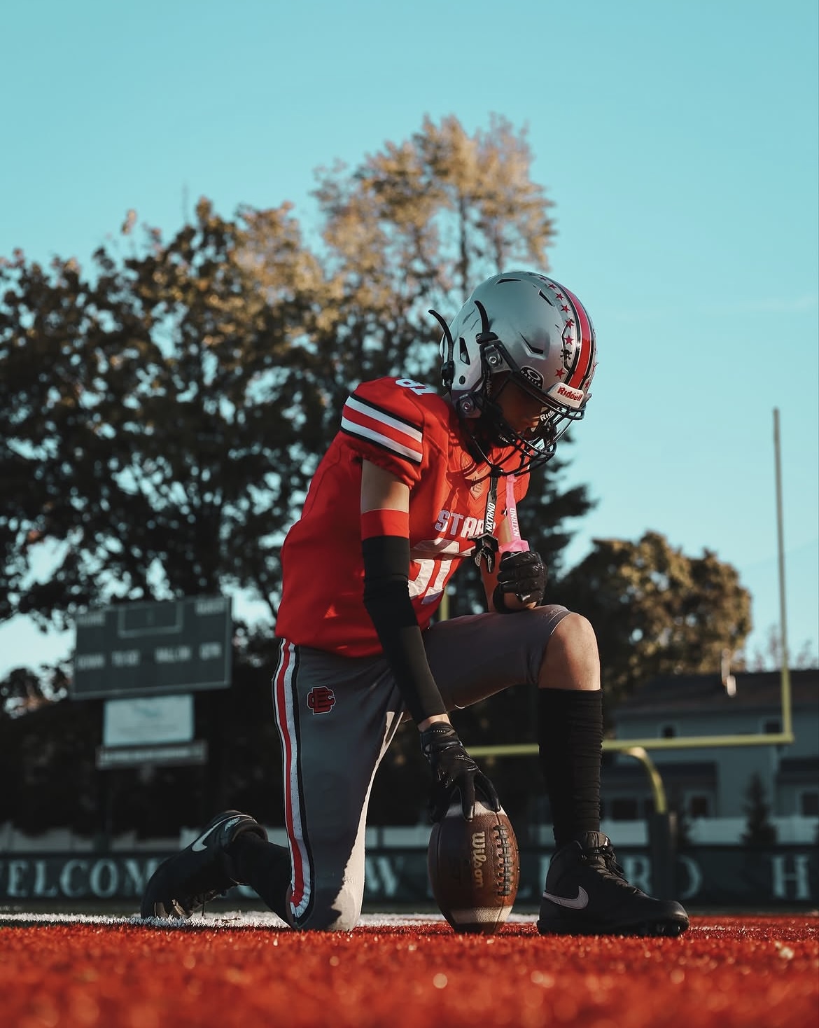 Football player kneeling with hand on the ball at the goal line at golden hour