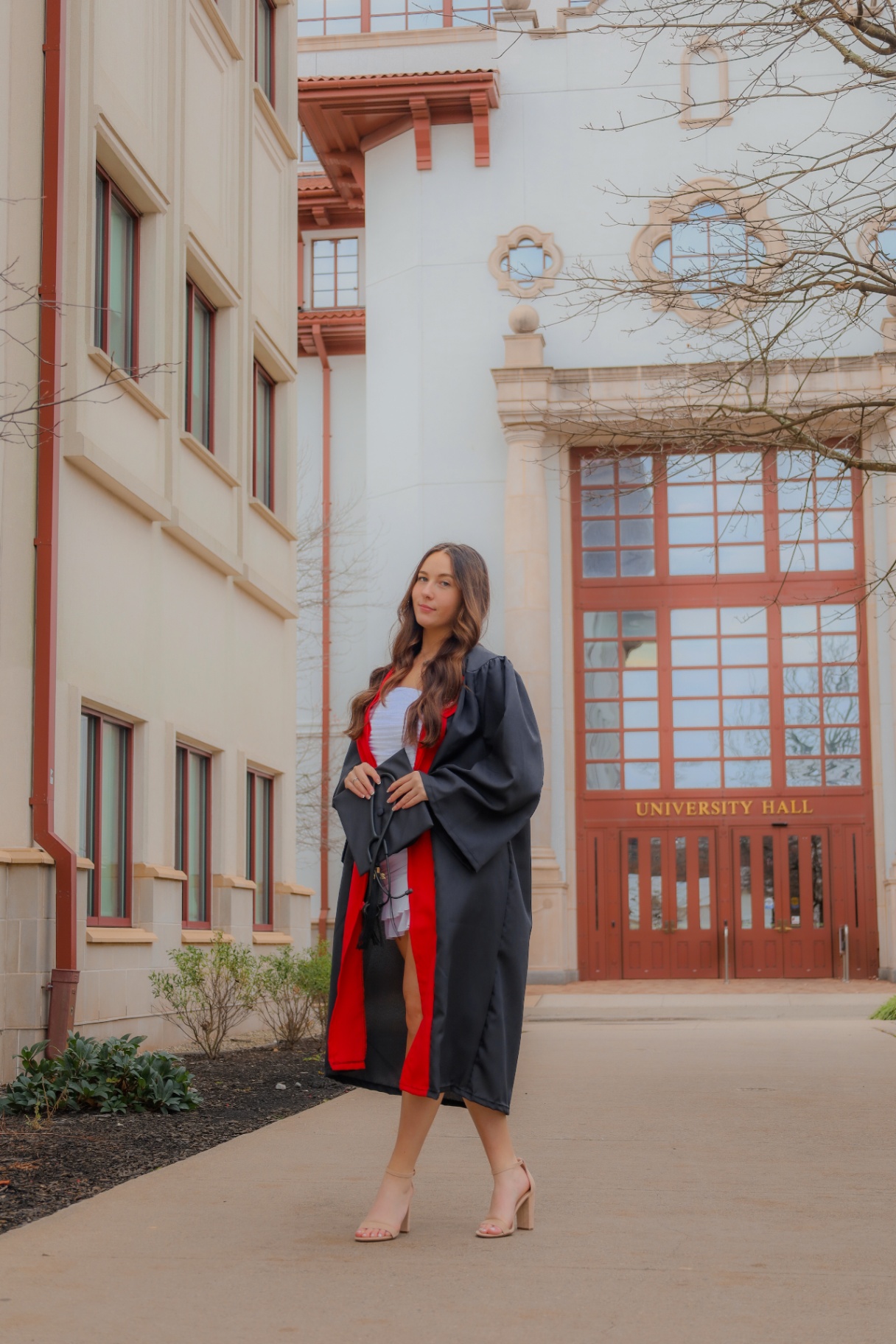 Graduate in gown posing in front of University Hall