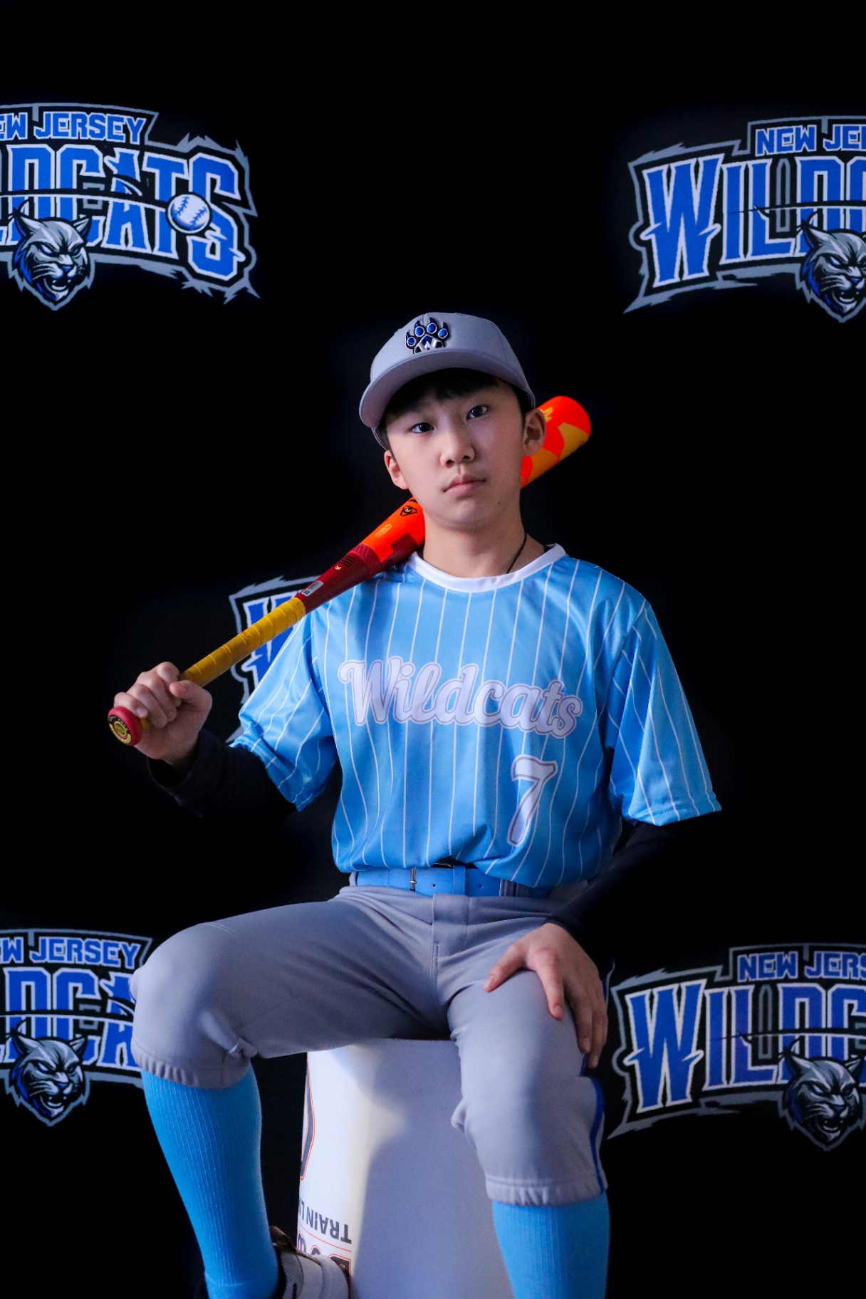 Portrait of a young baseball player seated with bat across shoulders