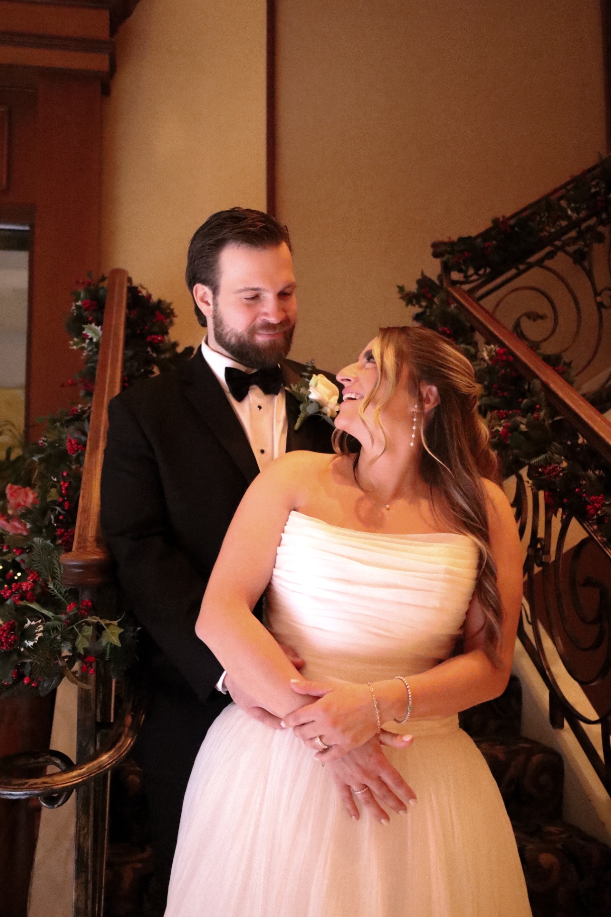 Bride and groom laughing together on a garland-draped staircase