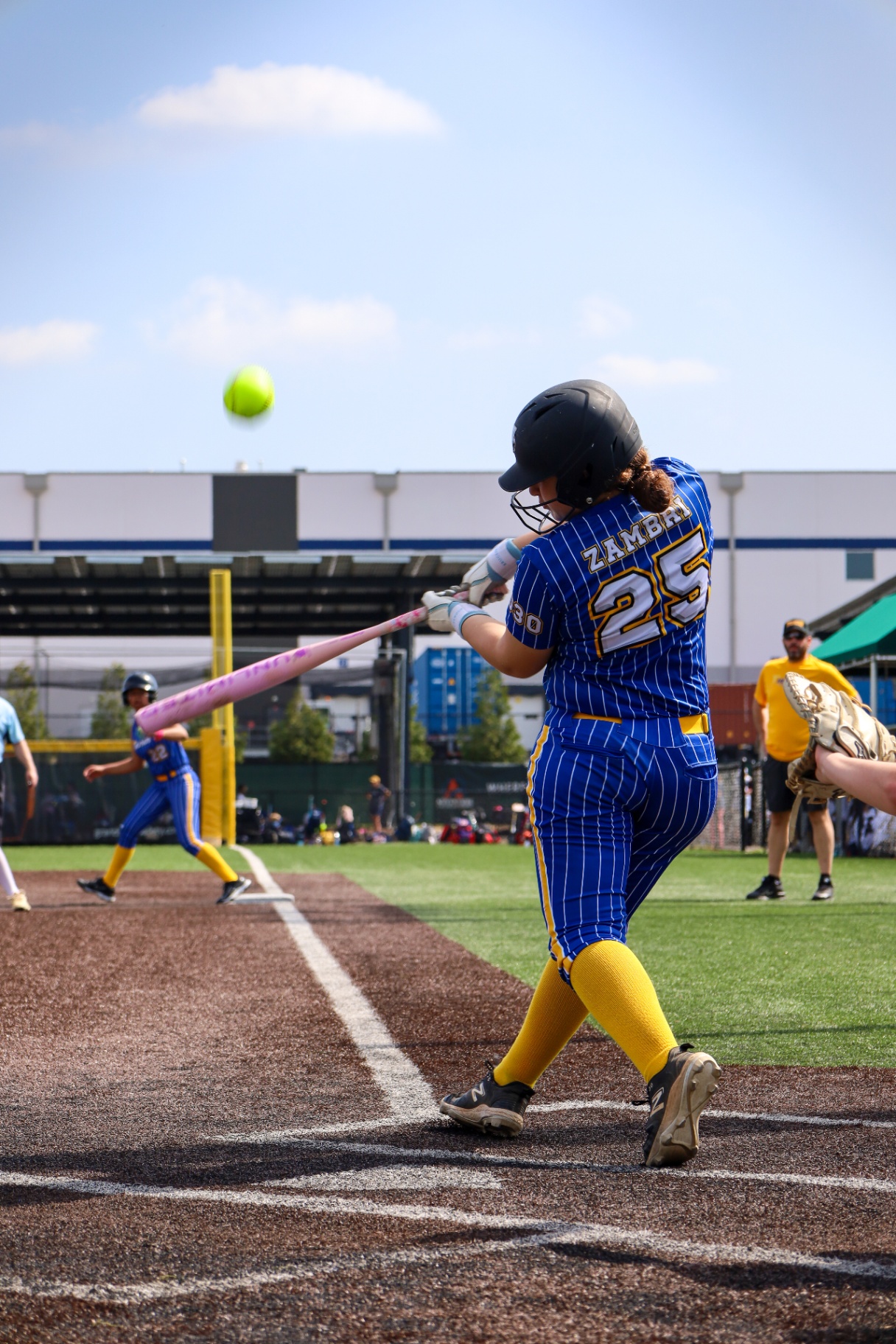 Softball player swinging through contact during game action
