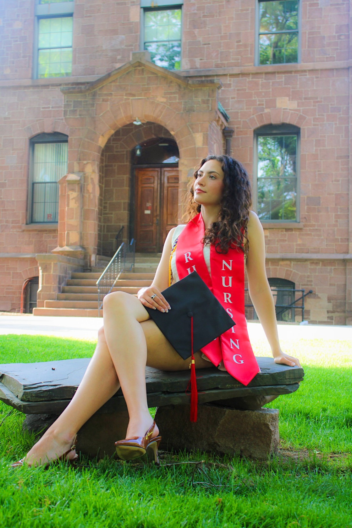 Rutgers Nursing graduate seated on stone bench