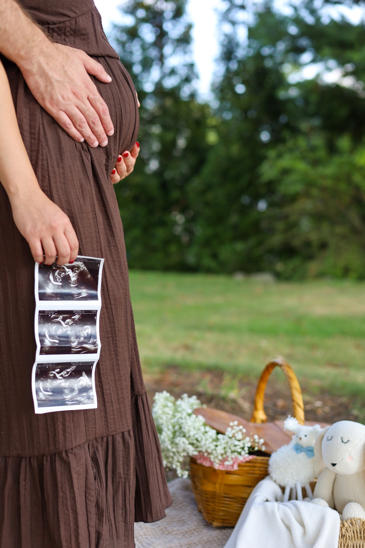 Pregnancy announcement with parents holding ultrasound photos beside the baby bump