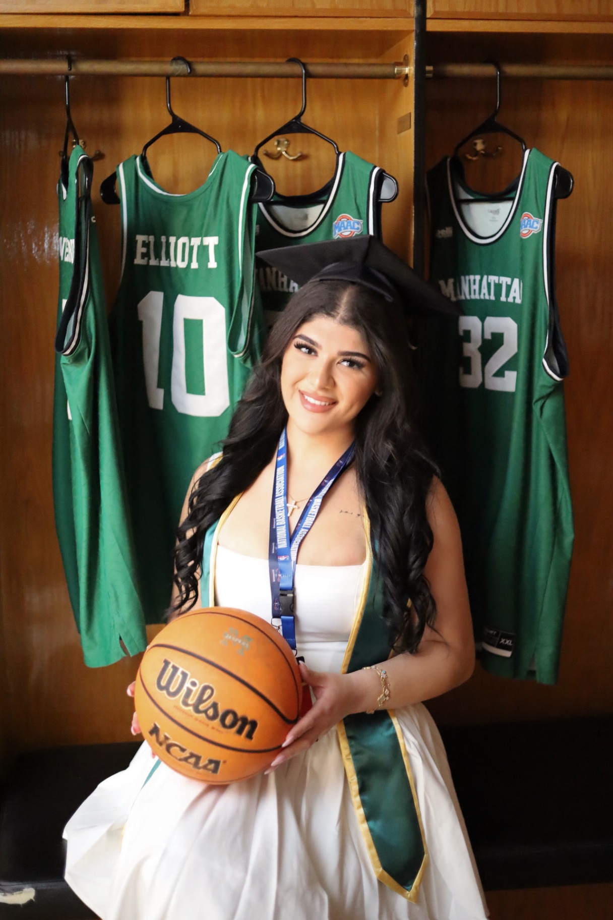 Graduate holding a basketball in a locker room portrait