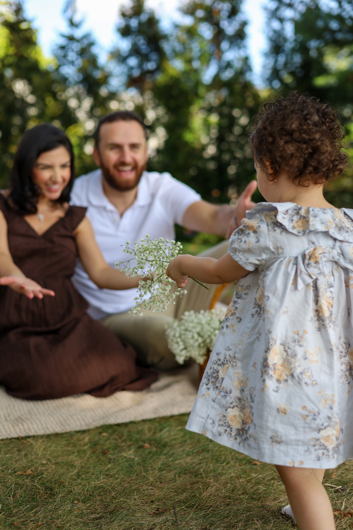 Toddler running into her parents' arms during a family pregnancy announcement session