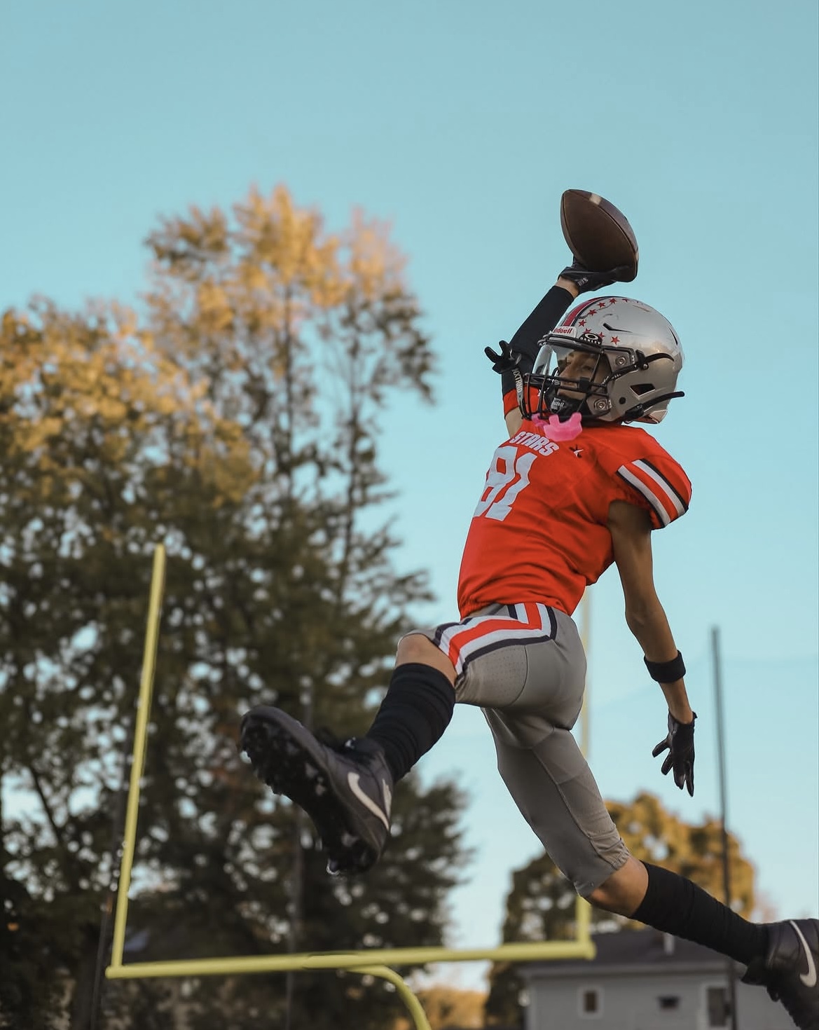 Youth football receiver leaping to make a one-handed catch in the end zone