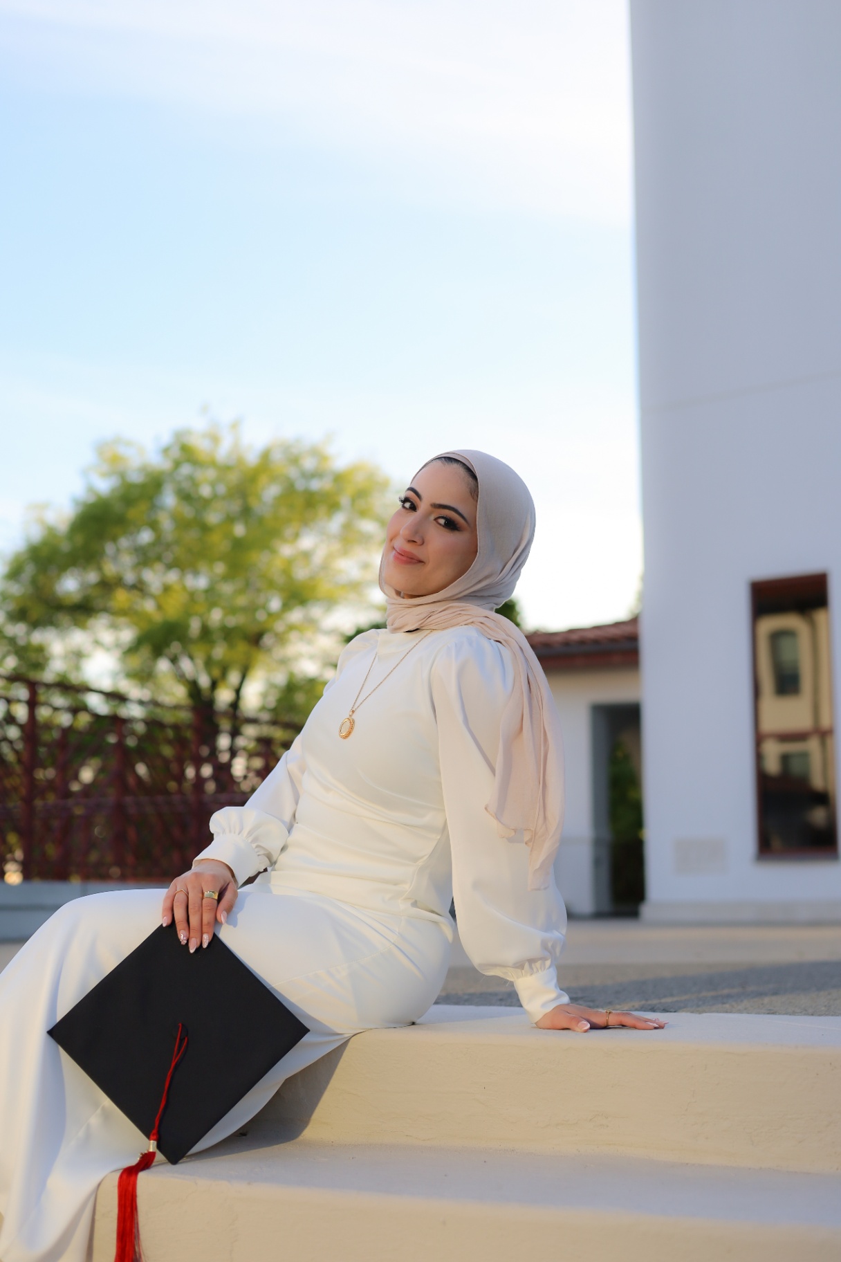 Seated portrait of graduate in white with cap