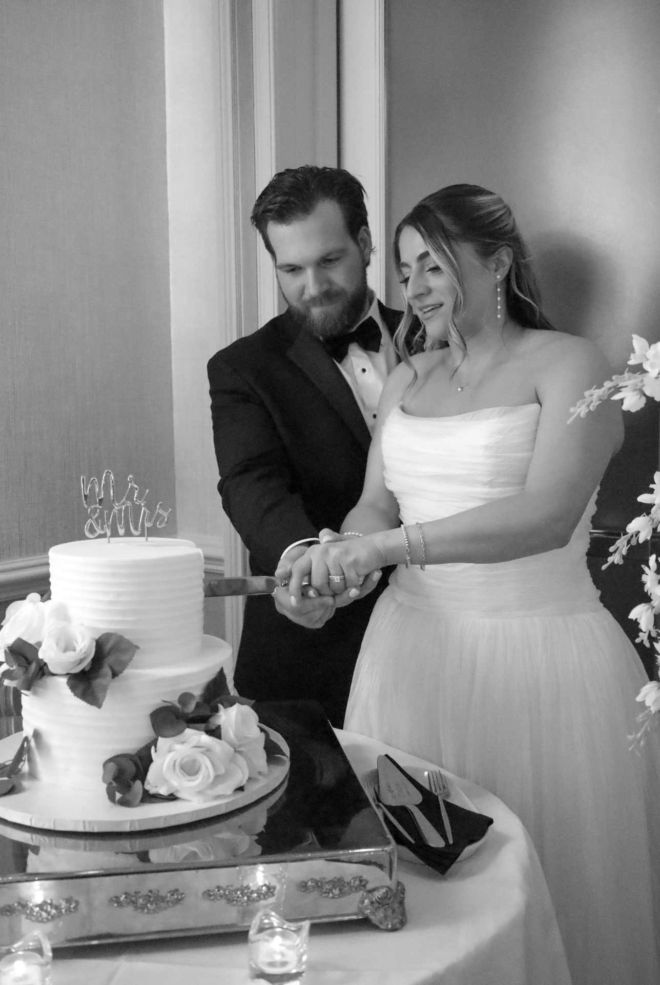 Black and white photo of the couple cutting their wedding cake together