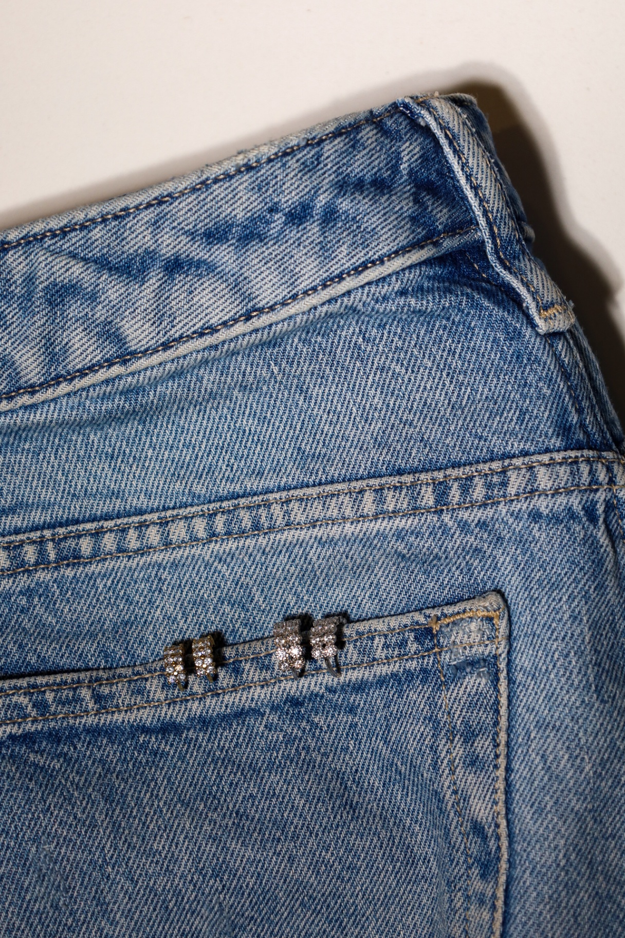 Close-up of sparkling earrings clipped onto a denim pocket