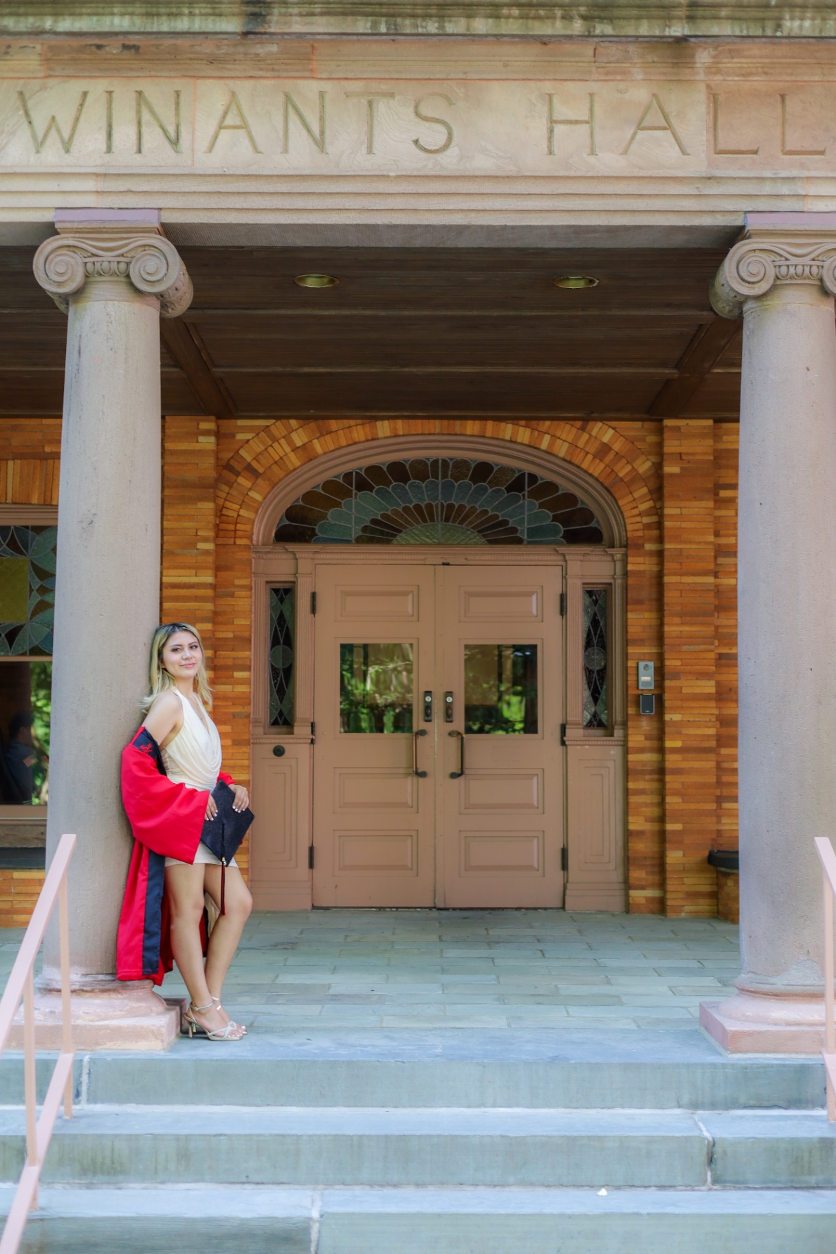 Graduate posing on the steps of Winants Hall at Rutgers