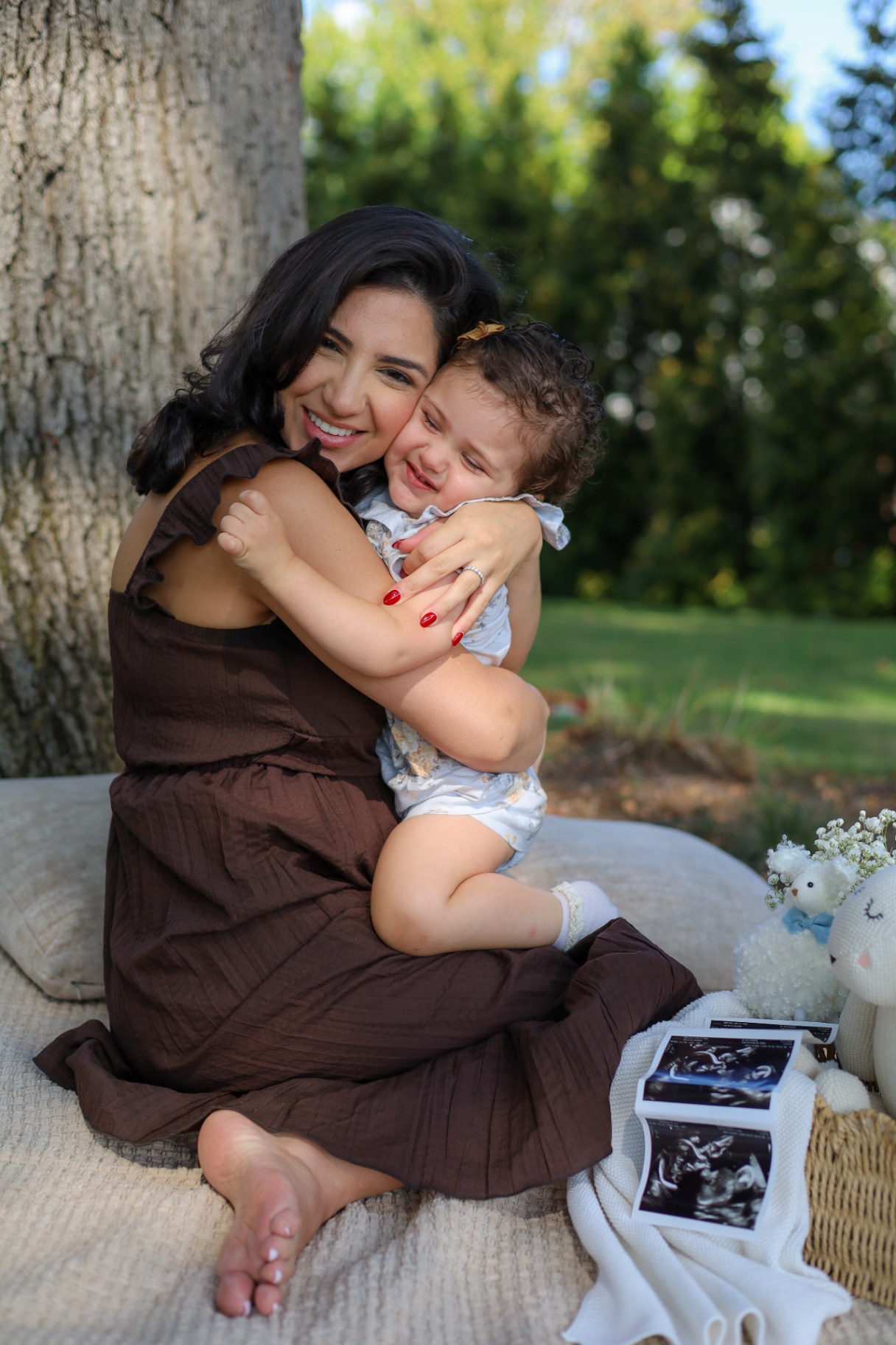 Mother and toddler daughter hugging at an outdoor pregnancy announcement session