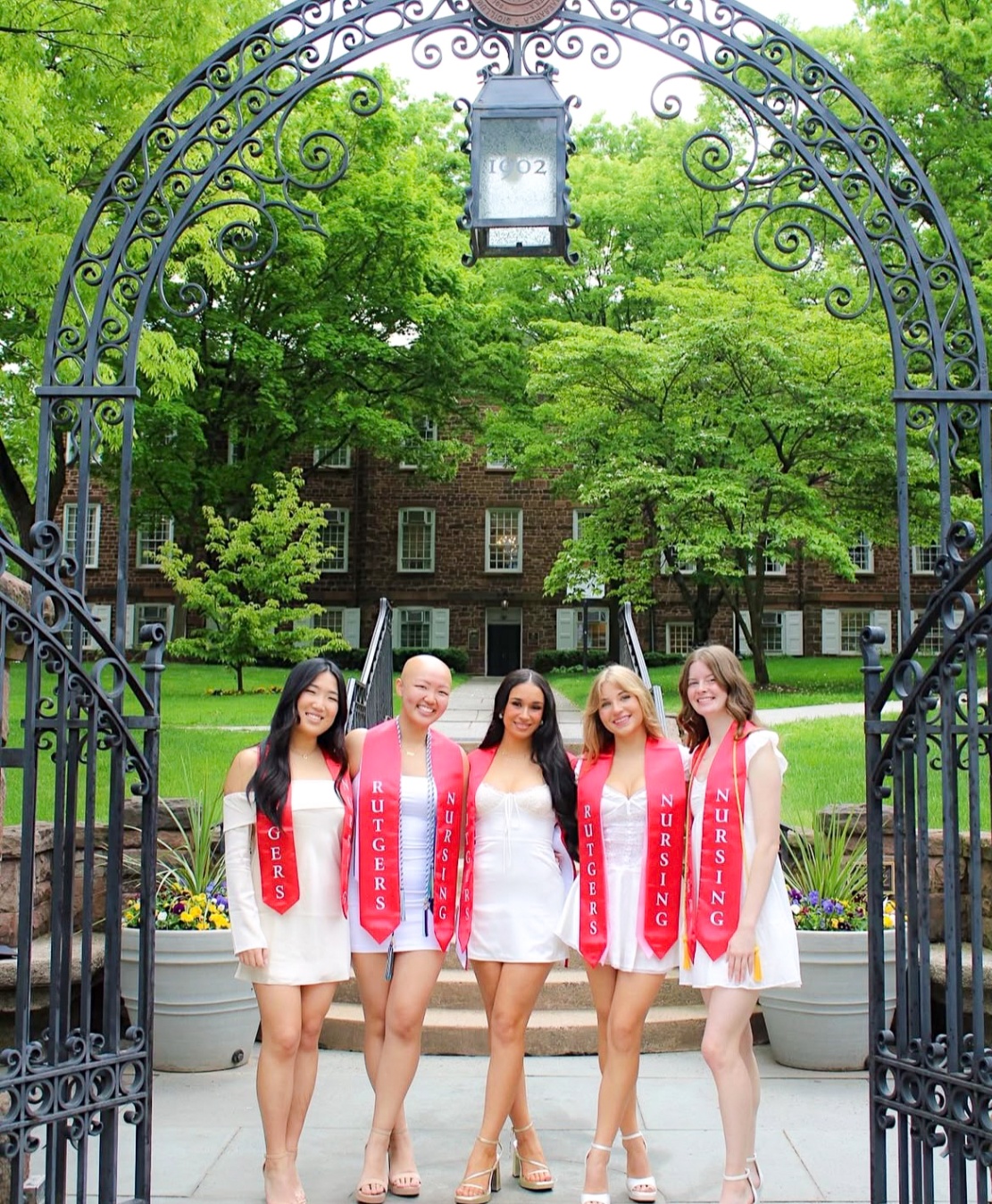 Group of Rutgers Nursing graduates beneath the campus arch