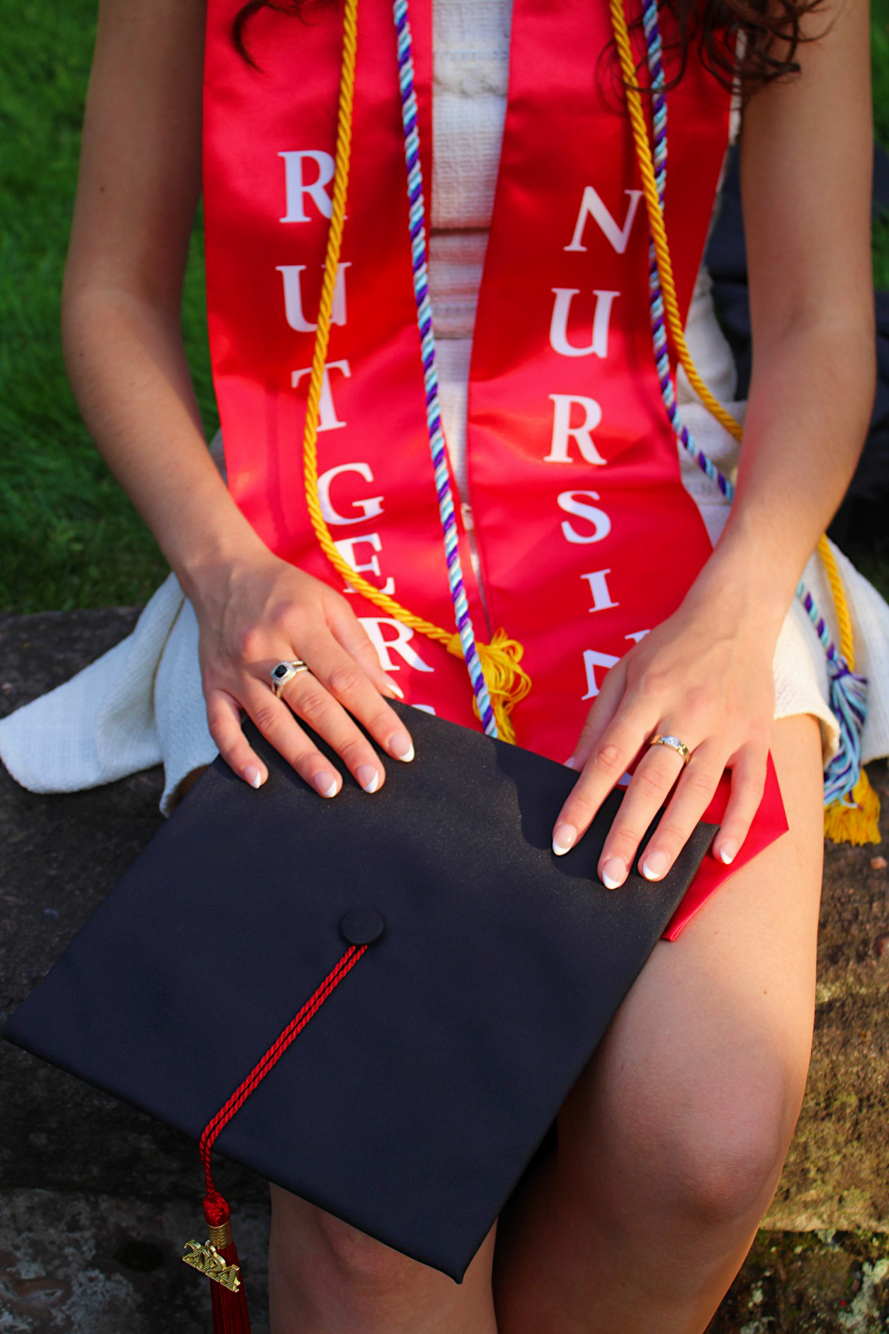 Close-up of Rutgers Nursing graduate's hands on her cap and red stole