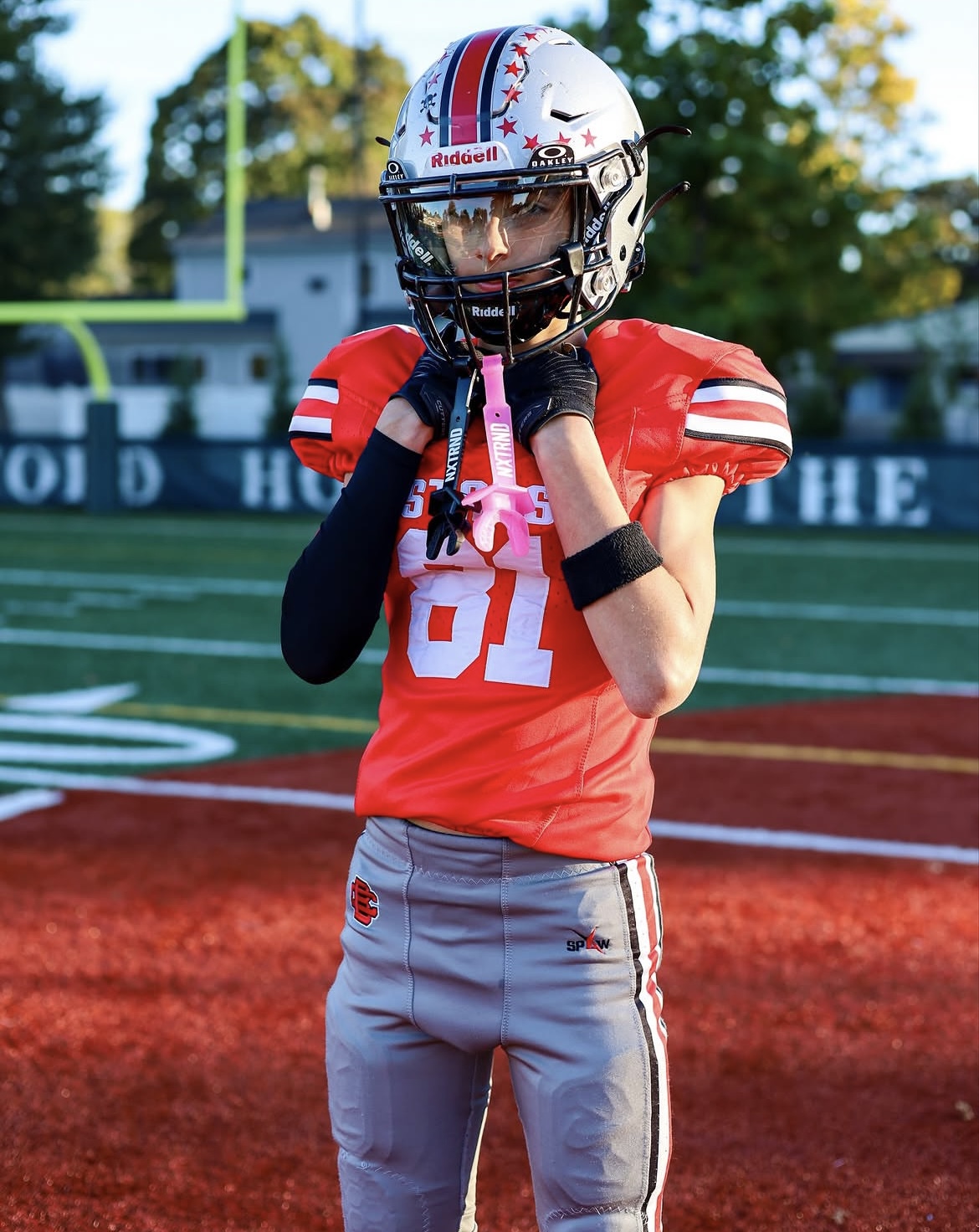 Football player adjusting chin strap on the field in dramatic light