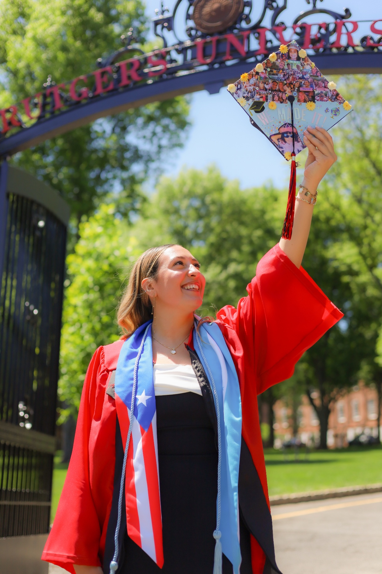 Graduate raising her decorated cap under the Rutgers arch