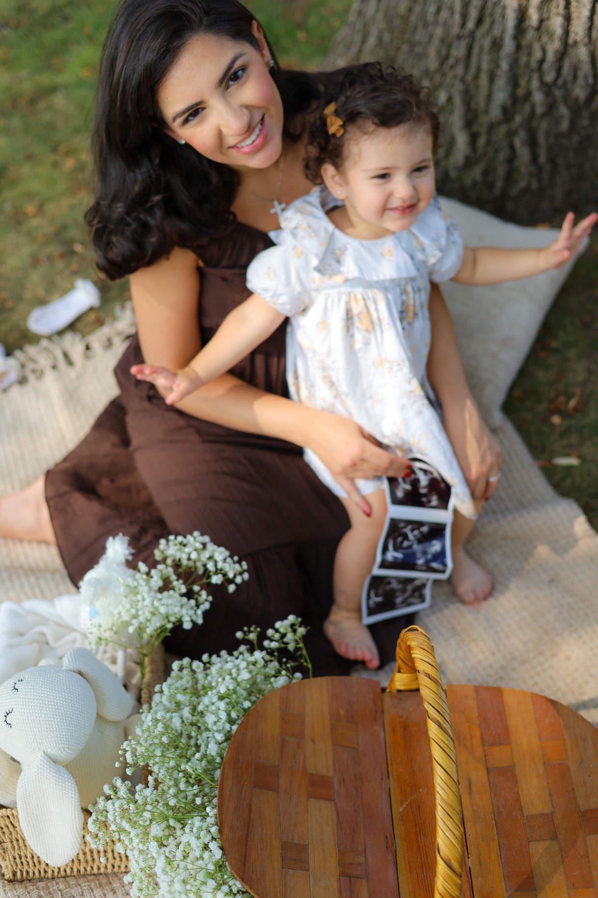 Mother and daughter laughing together with ultrasound photos at a maternity announcement