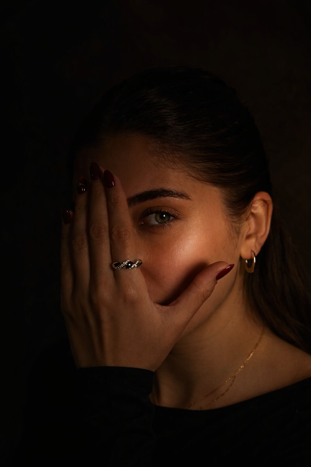 Moody beauty portrait featuring a statement ring and dramatic lighting