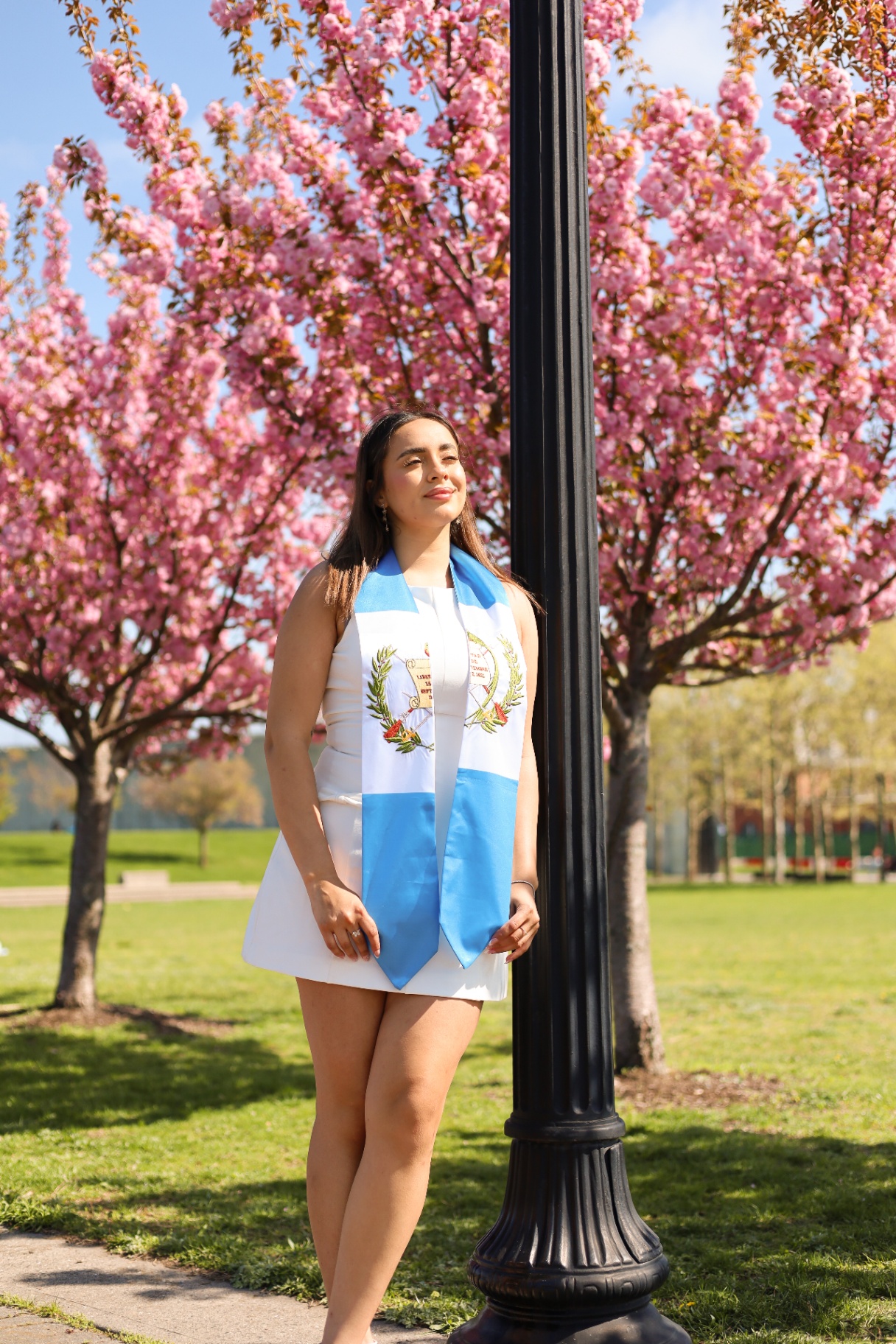 Graduate with Guatemala stole beneath cherry blossoms