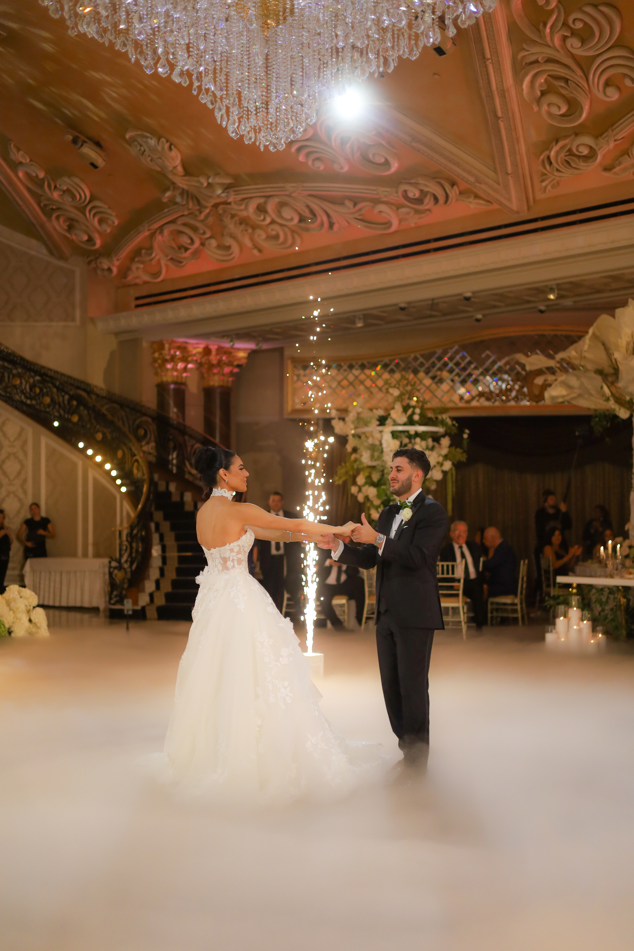 Bride and groom's first dance with fountain sparklers under a grand crystal chandelier