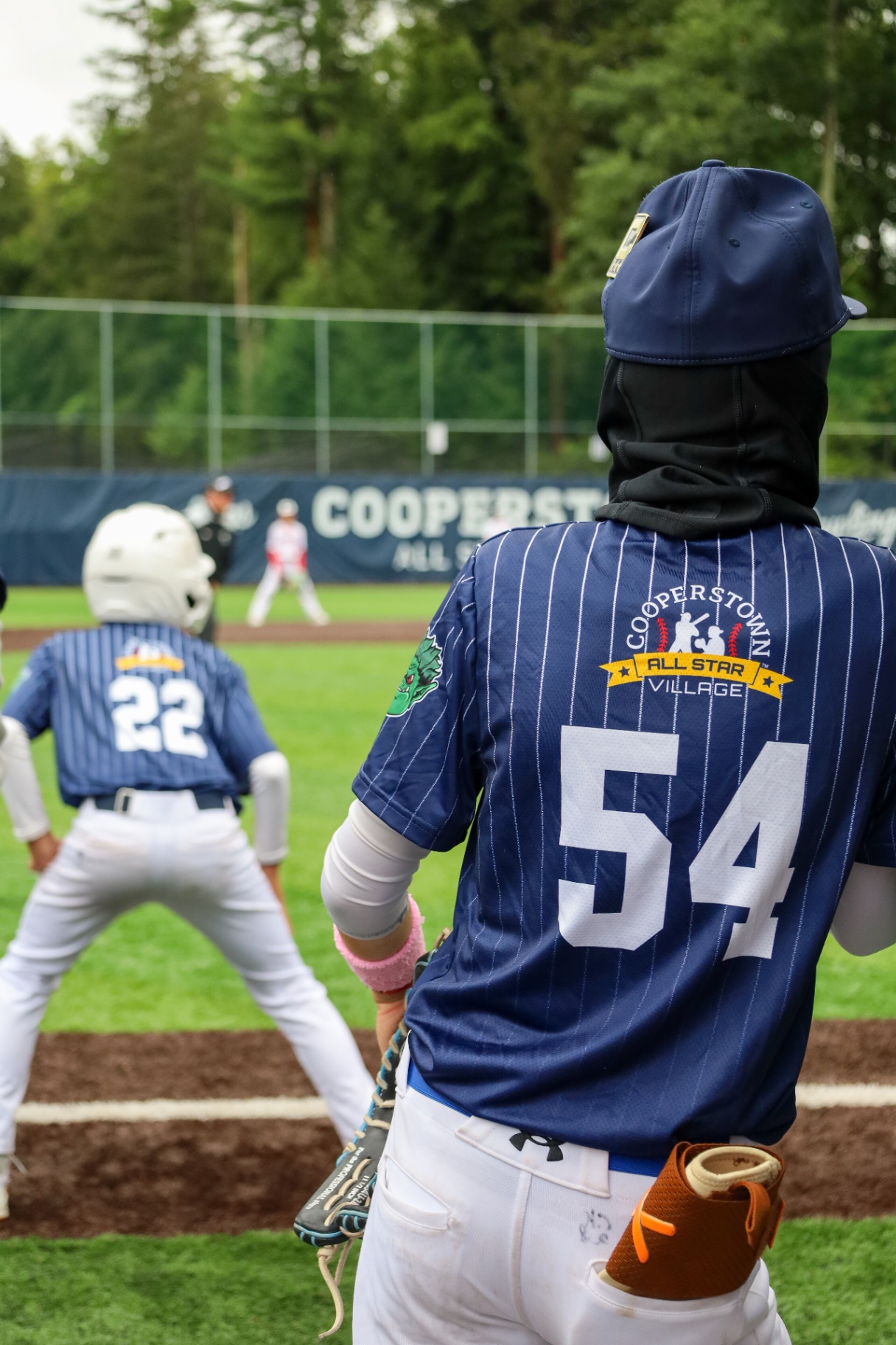 Player in Cooperstown jersey watching the infield from the baseline